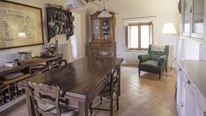 A dining area with a wooden table, chairs, and a hanging light fixture.