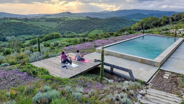 A swimming pool with a wooden deck and a person meditating.