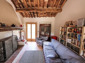 A cozy living room with a sofa, a bookshelf, and a wooden ceiling.