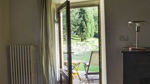 An open door leading to an outdoor area with a table and chairs, a radiator, and a lamp on a cabinet.