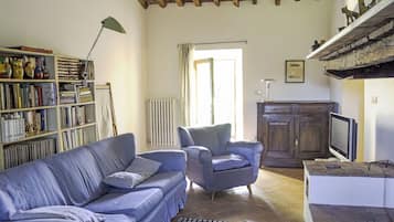 Un salon comprenant un canapé, un fauteuil et une bibliothèque remplie de livres et d’objets décoratifs.