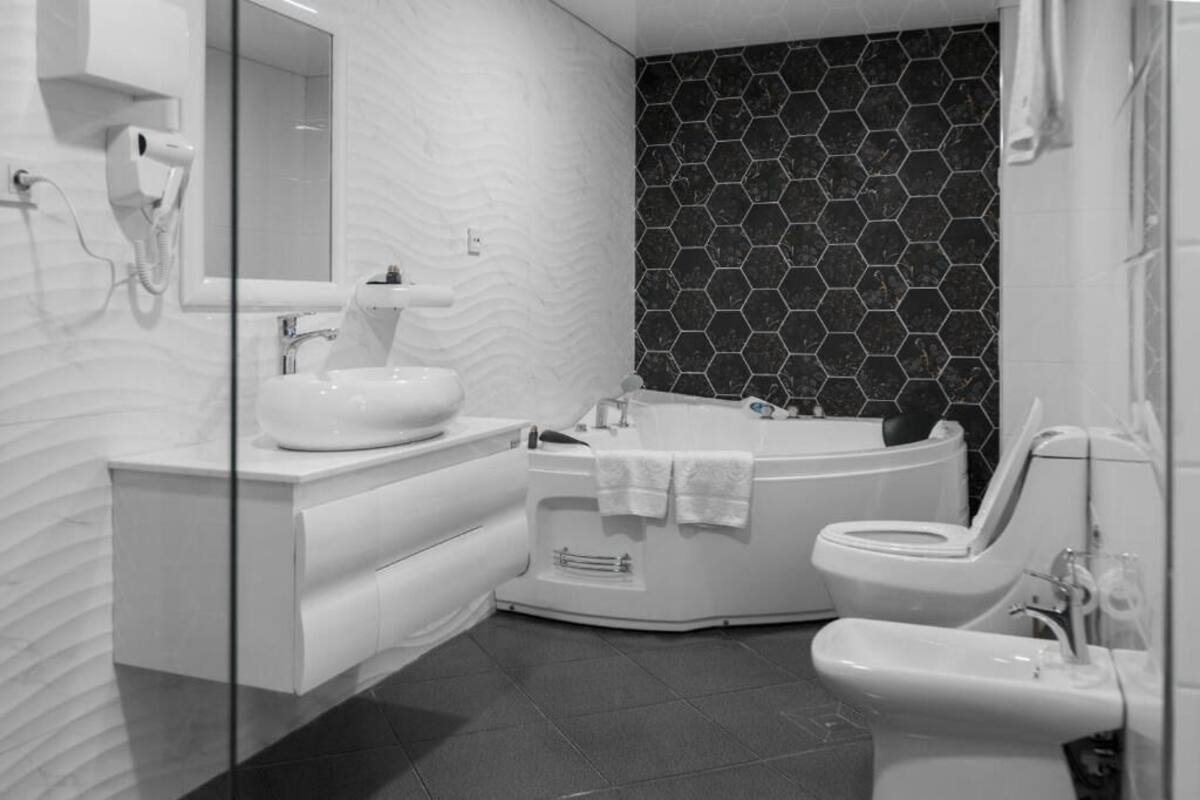 Ein modernes Badezimmer mit einem weißen Waschtisch, einer freistehenden Badewanne und einer Toilette.