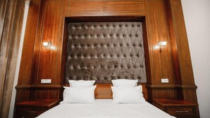 A bedroom with a tufted headboard, two bedside tables, and a large bed with white bedding. - Shedevr plaza (Namangan)