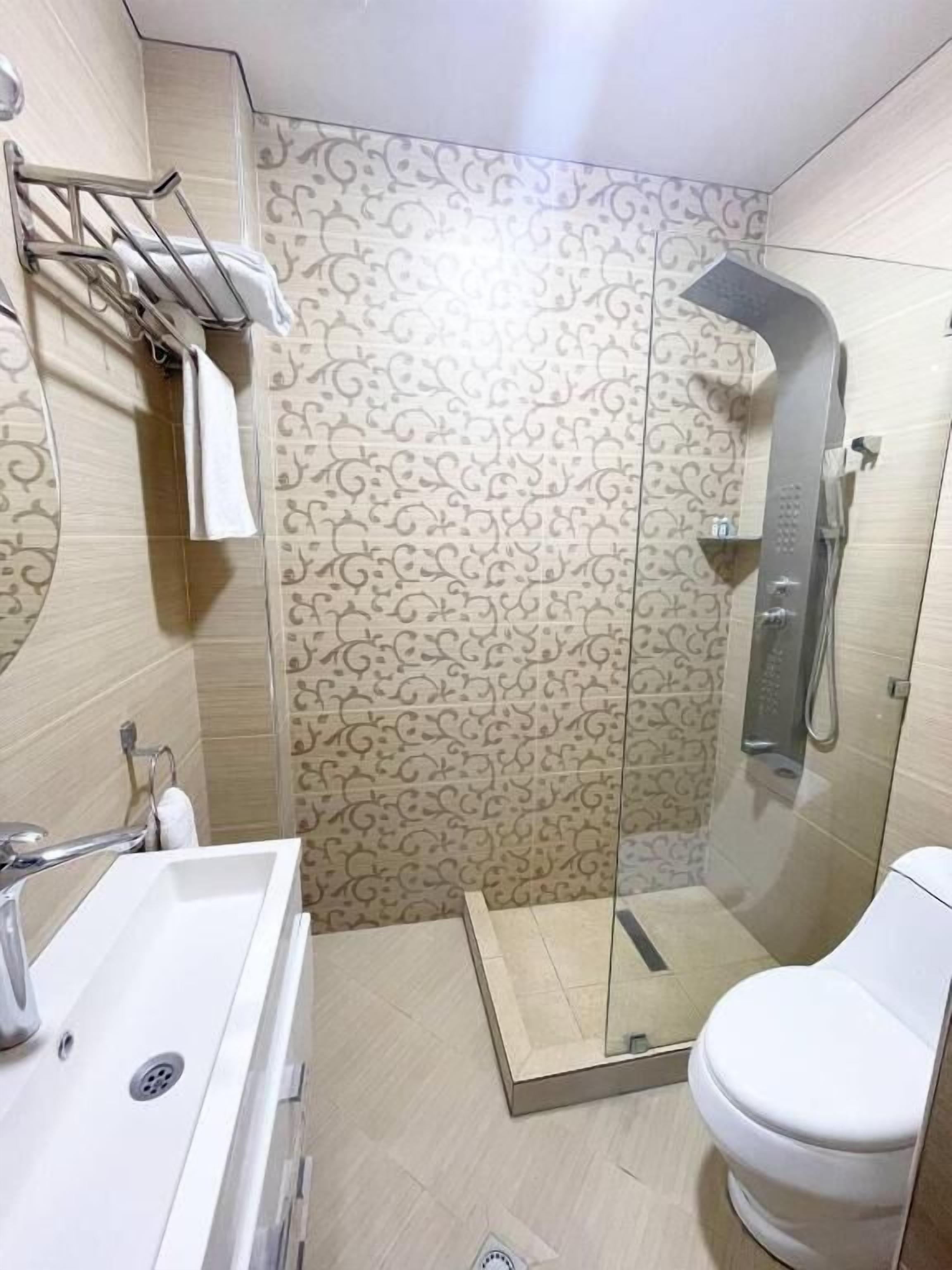 Ein modernes Badezimmer mit Duschkabine aus Glas, einem weißen Waschbecken und einer Toilette.