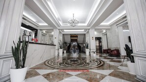 A spacious lobby with a checkered marble floor, a central chandelier, and a reception desk. - Shedevr plaza (Namangan)