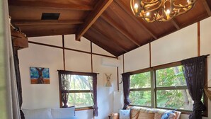 A room with a bed, a sofa, a chandelier, and large windows. - Mary River Hideaway - Bush Turkey Retreat a place to unwind surrounded by nature (Conondale)