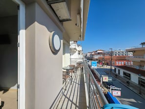 Un balcón con vista a una calle y edificios. Hay un letrero redondo en la pared y un letrero azul con texto.