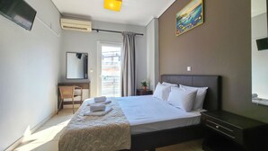 A hotel room with a bed, a desk, a chair, a TV, and a painting on the wall.