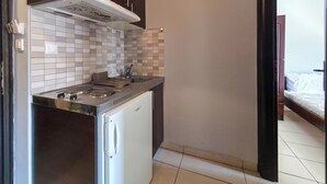 A compact kitchen with a stove, sink, and white tiled backsplash.