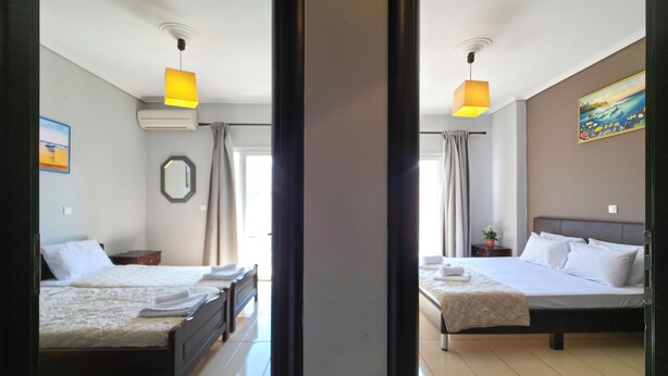 A hotel room with two beds, a large mirror, a painting, and a potted plant.