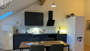 Una cucina moderna con mobili scuri, un tavolo da pranzo in legno e una lampada a sospensione.