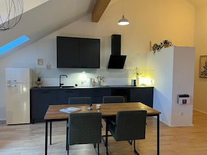 Eine moderne Küche mit dunklen Schränken, einem Holztisch und einer Pendelleuchte.