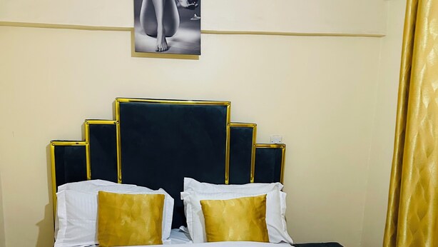 A neatly made bed with white and gold bedding, a dark headboard, and a towel on the bed. - ✨ Elegant 1-Bedroom  – Comfort, Class & Peace ✨

📍 Located along TRM Drive (Nairobi)