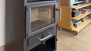 Une cuisine moderne dotée d’un poêle à bois encastré, d’une étagère en bois remplie de livres et d’un téléviseur posé sur un meuble en bois.