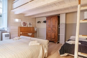 Un dormitorio con dos camas, un armario de madera, un radiador y una ventana.