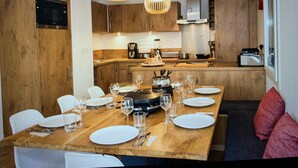 A modern kitchen with wooden cabinets, a central island with dining setup, and pendant lighting. - Apartment "Les Loges Blanches 101" with Wi-Fi (Châtel)
