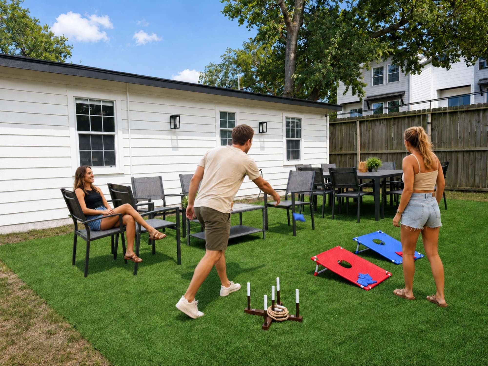A backyard with artificial grass, a wooden deck, and a dining area with chairs and tables.