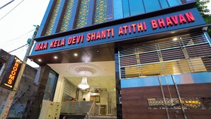 Entrada de um hotel com uma placa que diz 'MAA KELA DEVI SHANTI ATITHI BHAV'.