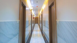 Um corredor de hotel com pisos e paredes de mármore, iluminado por iluminação embutida.