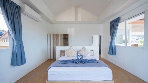 Moderni hotellihuone, jossa on suuri sänky, vaatekaappi ja näkymä ulos.
