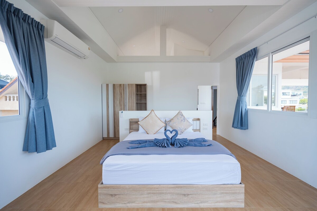 Ein modernes Hotelzimmer mit einem großen Bett, einem Kleiderschrank und Blick ins Freie.