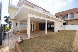 Uma casa moderna de dois andares com varanda coberta, área de cozinha visível e gramado bem cuidado.