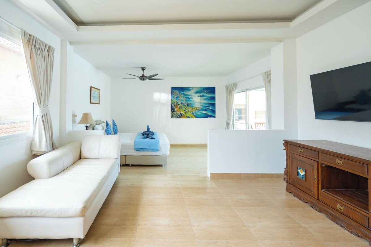 Ein modernes Wohnzimmer mit einer Couch, einem Fernseher, einem Deckenventilator und einem Gemälde an der Wand.