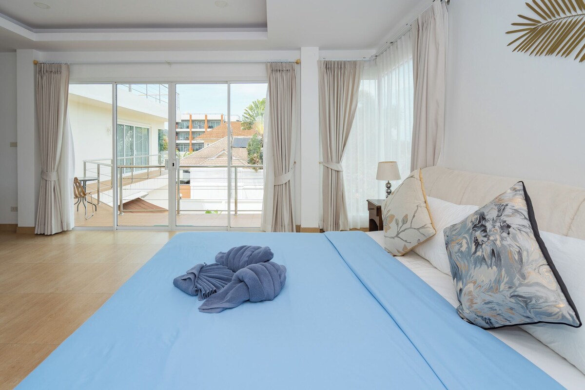 Ein Hotelzimmer mit Bett, Sofa, Lampe und Blick ins Freie.