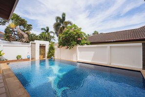 Ein Swimmingpool mit weißem Zaun, Palmen und blauem Himmel.