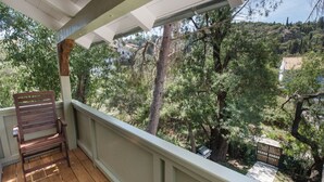 Una terraza de madera con un banco, con vistas a un jardín exuberante y un paisaje montañoso.