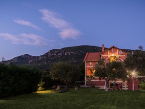 Ein zweistöckiges Haus mit rotem Dach und Satellitenschüssel. Es gibt einen Rasen mit einer Hängematte und einem Patio-Tisch.