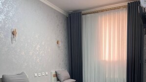 Ein modernes Schlafzimmer mit zwei Einzelbetten, einem Holznachttisch, einem kleinen Tisch und einer Wandleuchte.