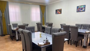 Ein Konferenzraum mit sechs Tischen und Stühlen, einer Kandelaber und einem Gemälde an der Wand.