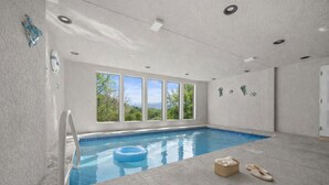 Una piscina interna con vista aperta sull'esterno, una scala per la piscina e un cerchio galleggiante.