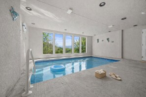 Ein Hallenbad mit freiem Blick ins Freie, einer Poolleiter und einem schwimmenden Ring.