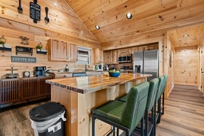 Un interior de madera con una zona de cocina, una barra de café y taburetes de bar.
