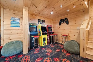 A wooden room with arcade games, a sign with gaming rules, and bean bags. - Majestic Horizon by Ghosal Luxury Lodging (Sevierville)