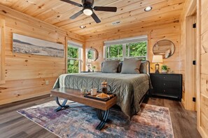 A wooden cabin bedroom with a bed, bedside table, and a ceiling fan. - Majestic Horizon by Ghosal Luxury Lodging (Sevierville)