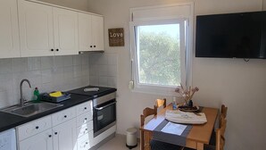 Eine moderne Küche mit weißen Schränken, einer schwarzen Arbeitsplatte, einem Einbauofen und einem Fenster mit Blick auf Bäume.
