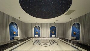 Ruime badkamer met sterrenhemel, marmeren vloer en drie wasbakken met gouden details.