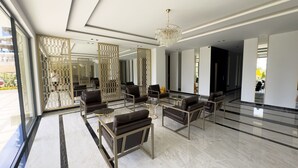 Een ruime lobby met modern meubilair, een kroonluchter en een uitzicht door een glazen wand.