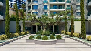 A modern multi-story building with balconies, a central courtyard with trees and shrubs, and a clear blue sky. - Qoople Eхсellence A-49 neue Wohnung am Meer by Interhome (Alanya)