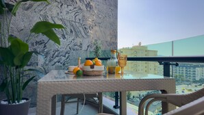 A balcony with a wicker table, a potted plant, a vase, and a view of the cityscape. - Qoople Eхсellence A-49 neue Wohnung am Meer by Interhome (Alanya)