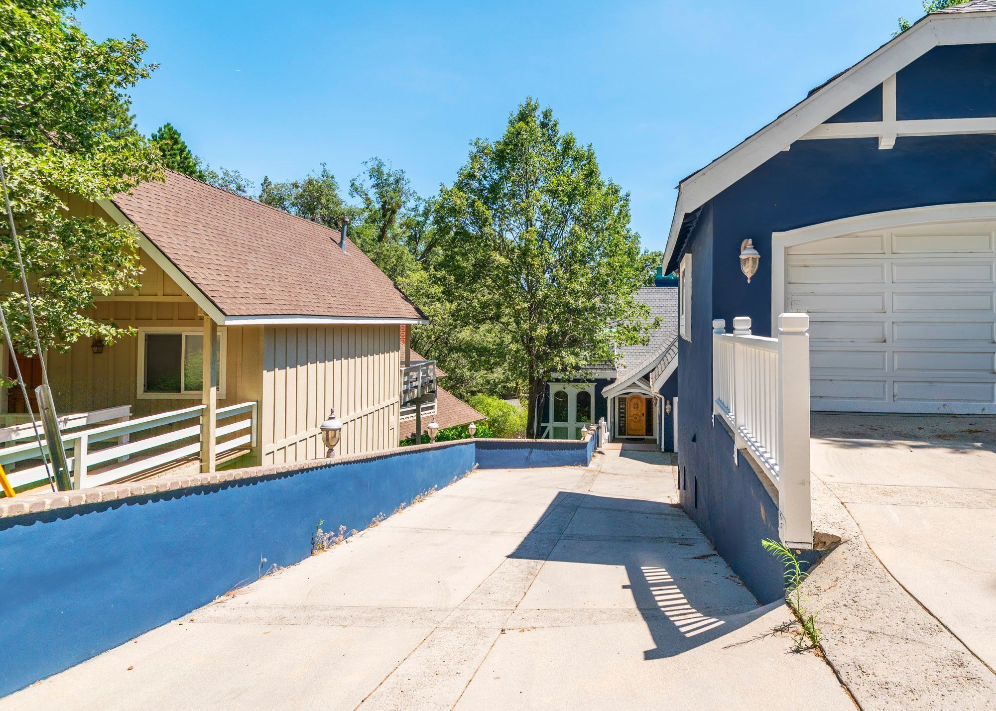 A residential property with a driveway leading to a garage, a small porch, and a fenced yard.