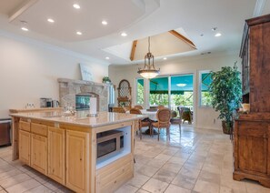 Una cocina espaciosa con una isla grande, armarios de madera y una chimenea de piedra.
