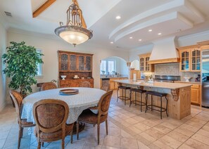 A spacious kitchen with a central island, wooden cabinets, and a dining area with a table and chairs. - Lake Arrowhead Waterfront Retreat | Game Room (Lake Arrowhead)