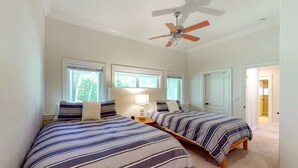 Une chambre avec deux lits, un ventilateur de plafond et une fenêtre.