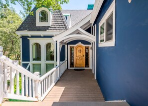 A house with a wooden front door, white railings, and a covered porch. - Lake Arrowhead Waterfront Retreat | Game Room (Lake Arrowhead)