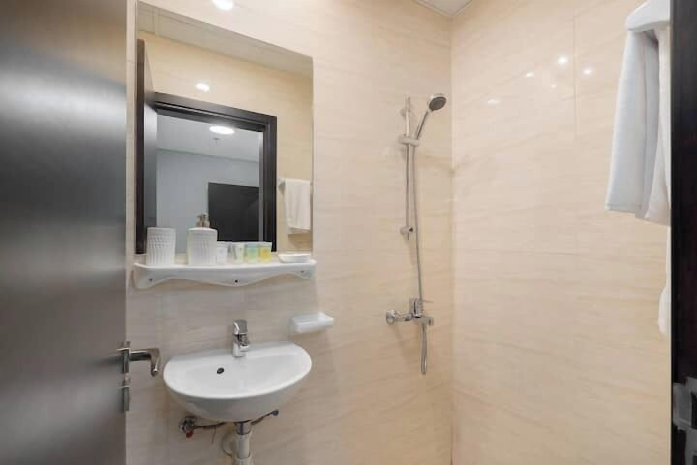 A bathroom with a sink, mirror, and shower.