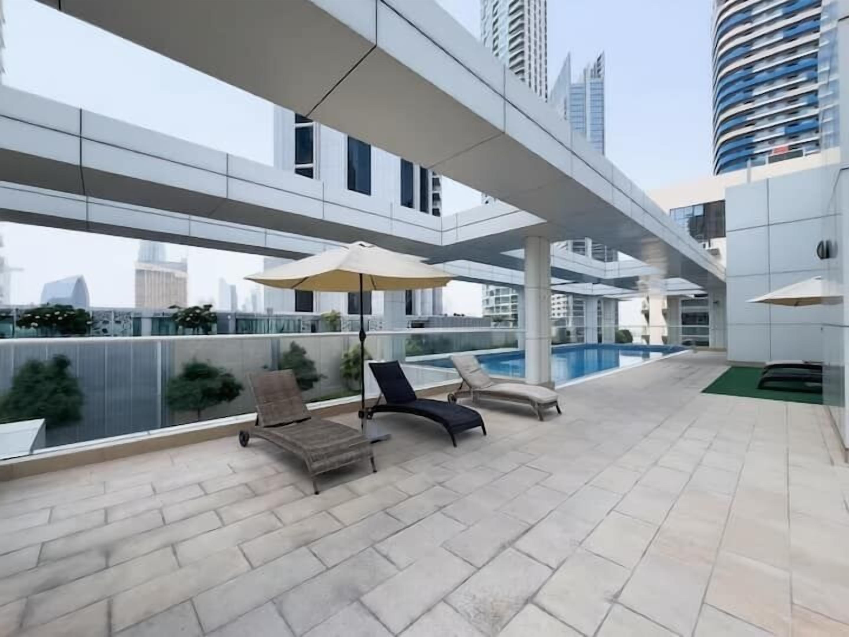 A rooftop terrace with a swimming pool, lounge chairs, and umbrellas.